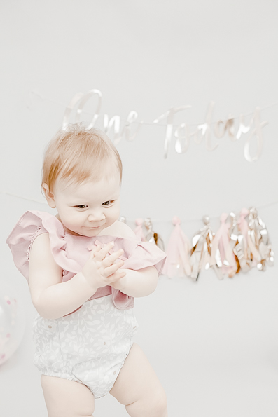Minimal, bright and airy first year birthday photography of baby girl on grey background studio set up