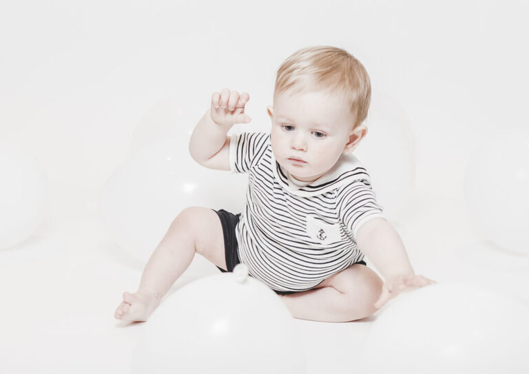 Natural Studio Photography,  minimal first birthday photoshoot of baby boy dressed in navy outfit shoot by petite feet photography in Woodford, London.