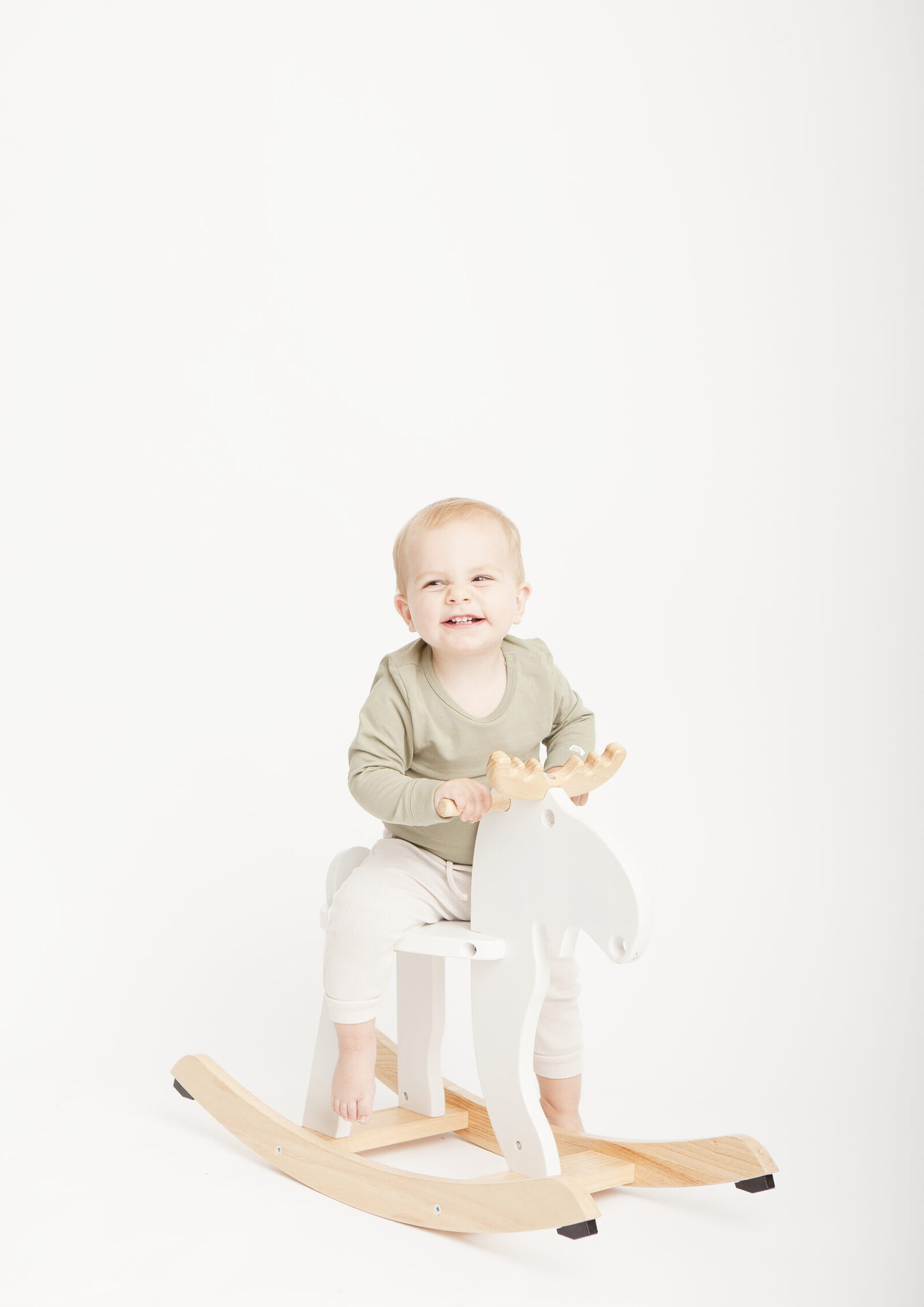 portrait of a boy on a rocking horse, minimal studio photography with white background by petite feet photography in London
